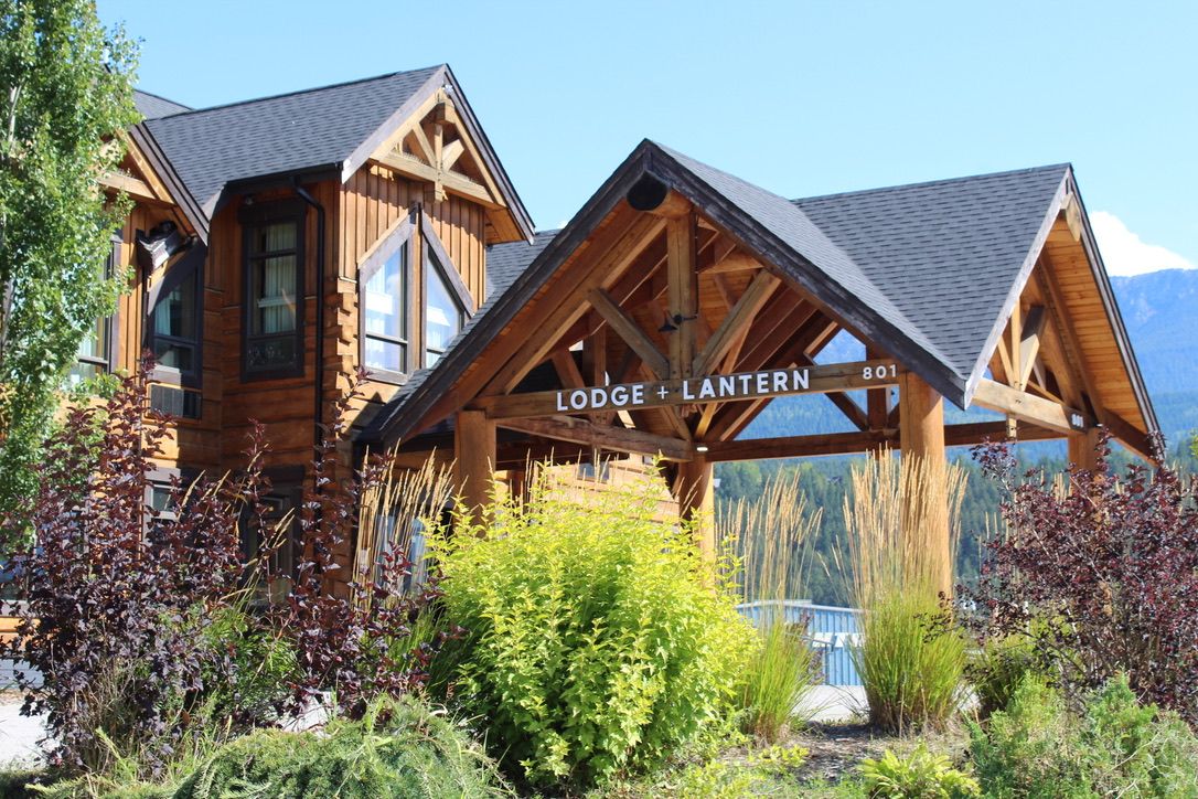 Una cabaña de madera con un porche cubierto, identificada con la señal 'Lodge + Lantern 801'.