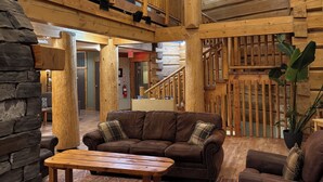 Ein großzügiger Innenraum mit einer Holztreppe, einem großen braunen Ledersofa und einem Holztisch.