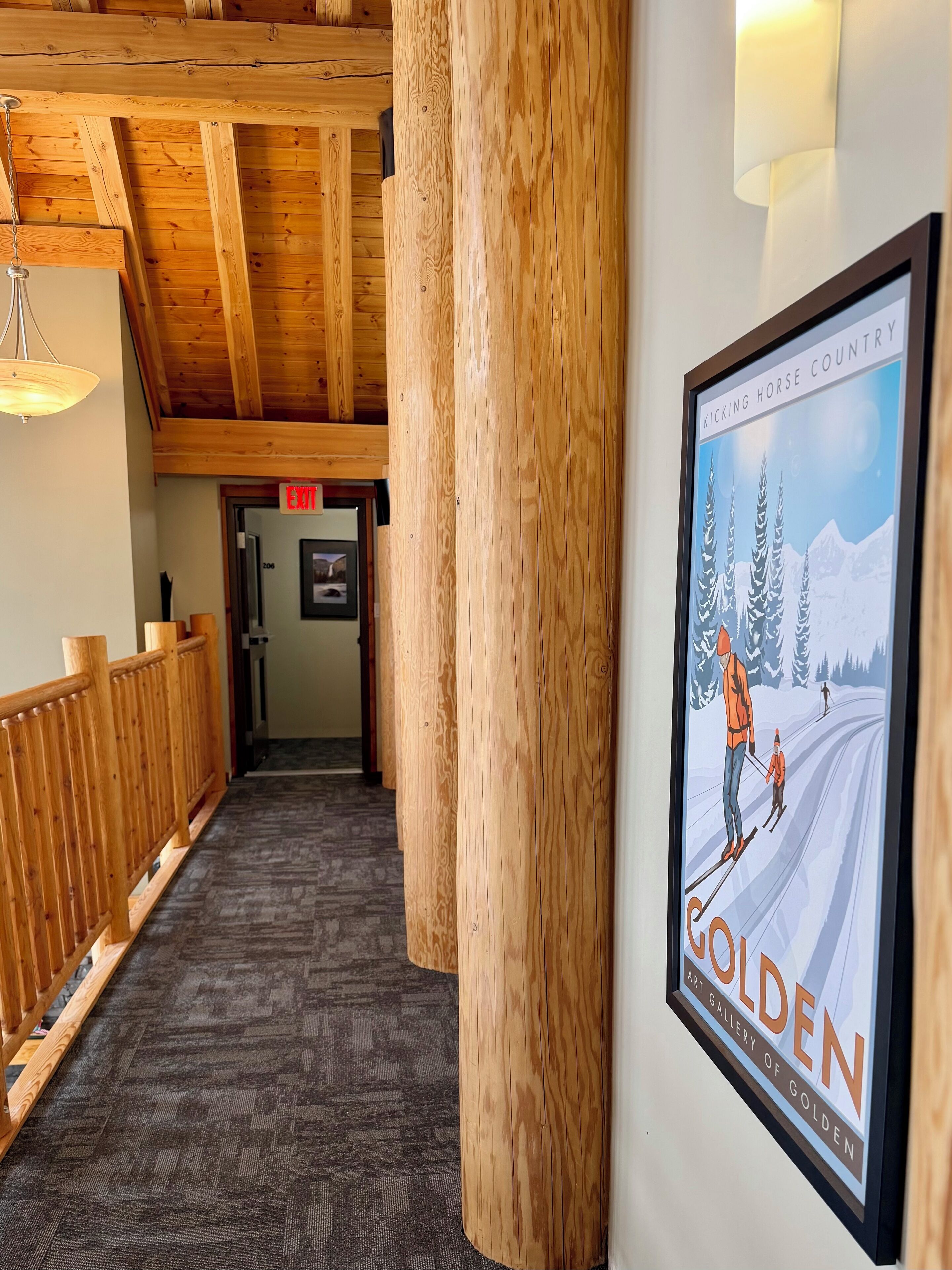 A hallway with wooden beams, a carpeted floor, and a framed poster of a skiing scene.