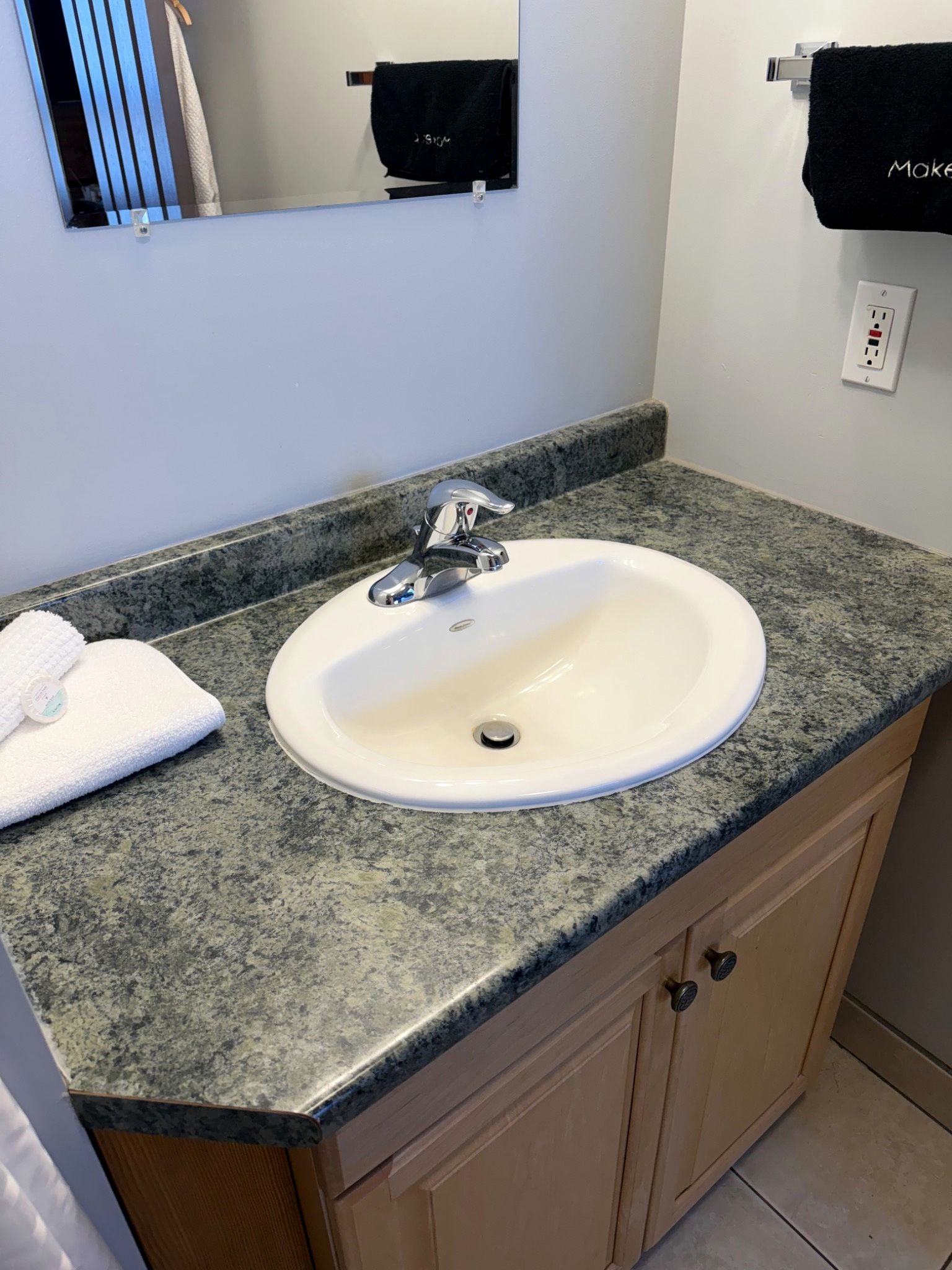 Un baño con lavamanos blanco, encimera de granito y muebles de madera.