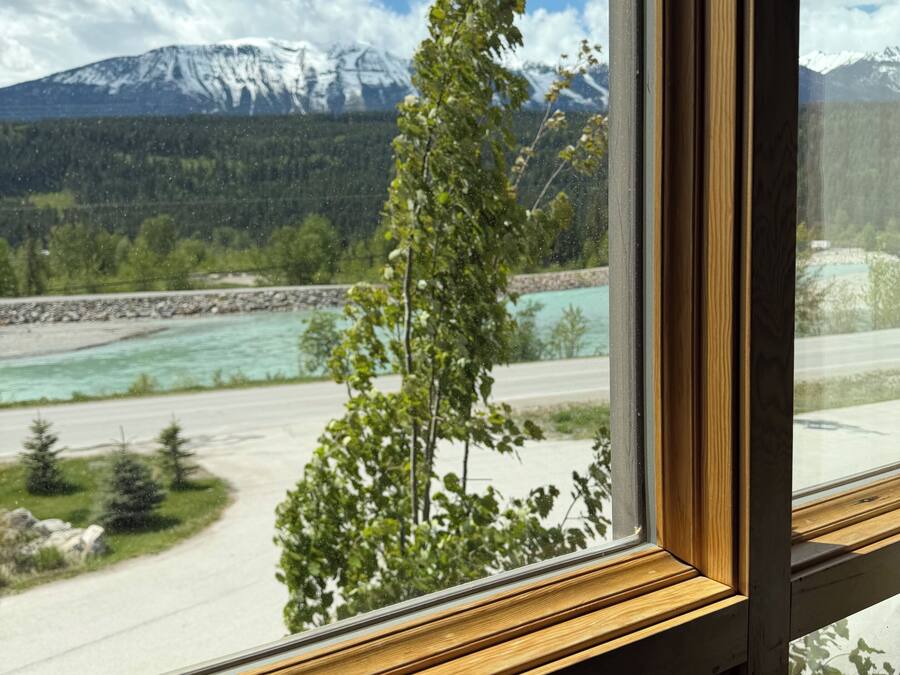 A window view of a river, mountains, and a tree.
