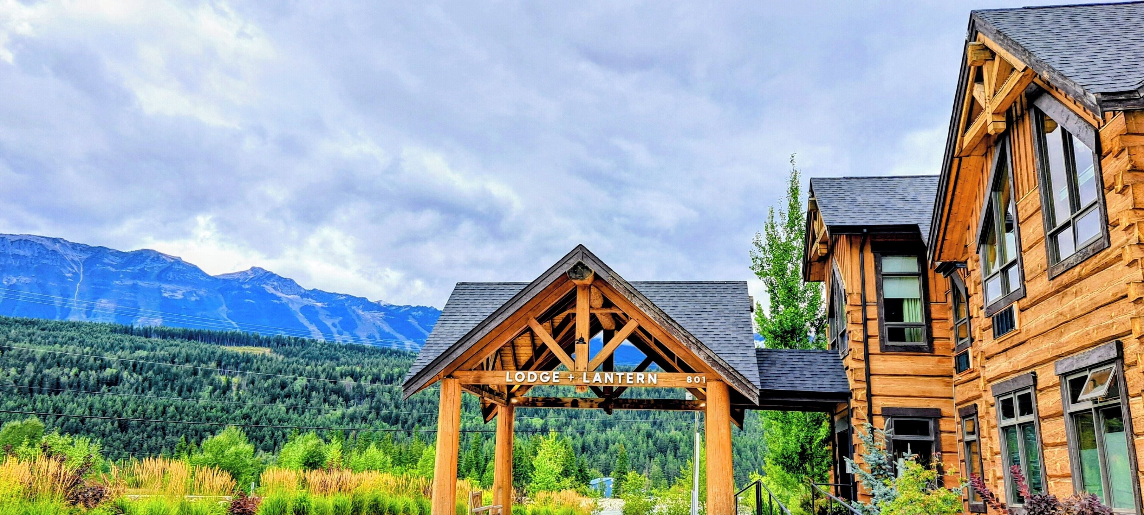 Una cabaña de estructura de madera con un letrero que dice 'Lodge + Lantern 801' al frente de un paisaje montañoso.