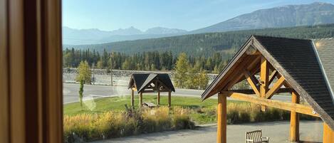 A view of a building with a sloped roof and wooden beams, a bench, and a road with a stop sign in the foreground.