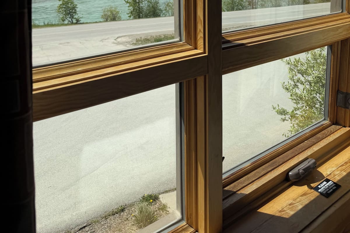 Una ventana con vista a una cordillera, un río y una carretera.