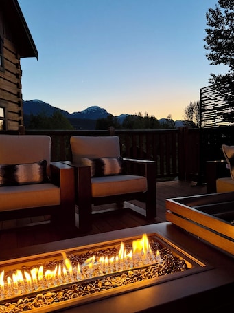 A patio with two chairs, a fire pit, and a view of mountains.