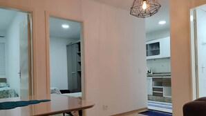 Un espacio habitable compacto con comedor, kitchenette y armario con espejo.