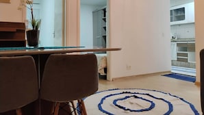 Una cocina moderna con armarios blancos, encimera de mármol e iluminación colgante.