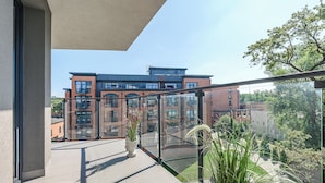 A modern building with large windows and a balcony with potted plants. - Luxury apart for family near Księży Młyn (Łódź)