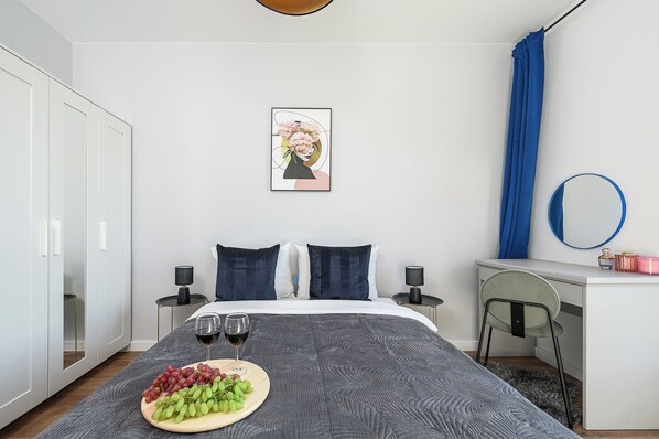 Un dormitorio moderno con cama, mesitas de noche, un escritorio, una silla y un cuadro enmarcado en la pared.
