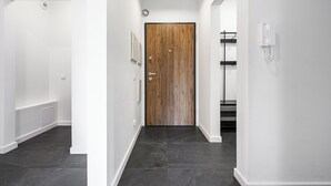 A modern hallway with a wooden door, a telephone, and a radiator. - Luxury apart for family near Księży Młyn (Łódź)
