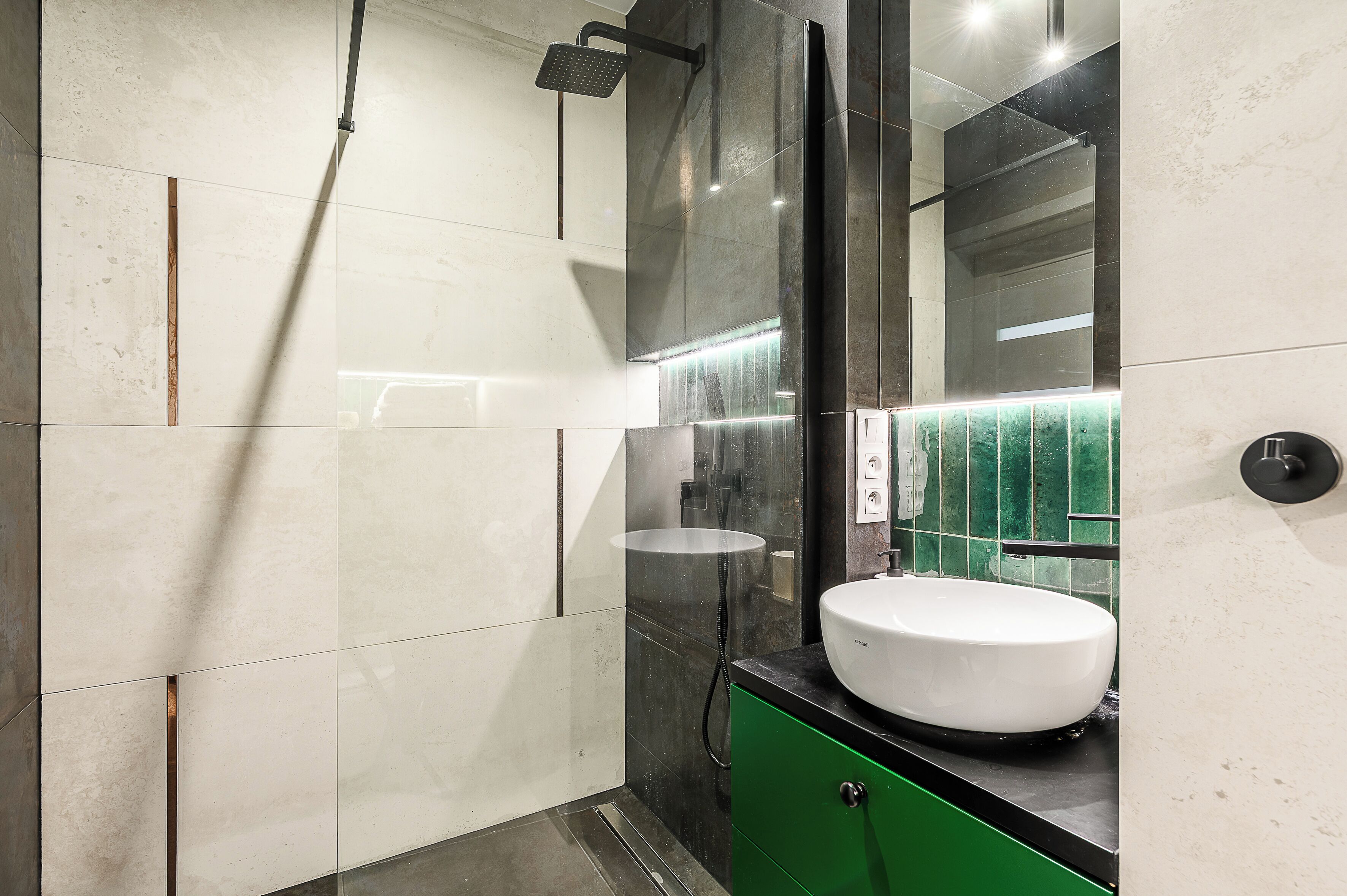 Une salle de bain moderne avec un grand miroir, un lavabo blanc et un espace douche.