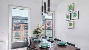 A dining area with a long table set for six, a vase with flowers, and framed botanical prints on the wall. - Luxury apart for family near Księży Młyn (Łódź)