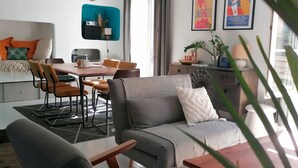 Un salon moderne comprenant un canapé, des fauteuils, une table à manger et un téléviseur.