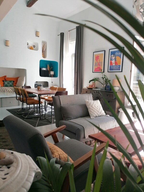 A modern living room with a sofa, chairs, a dining table, and a TV.