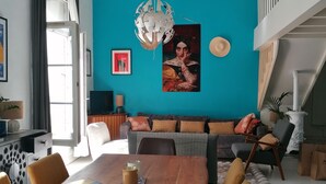 Un salon moderne avec un mur d’accent de couleur turquoise, une table à manger en bois et un escalier menant à un niveau supérieur.