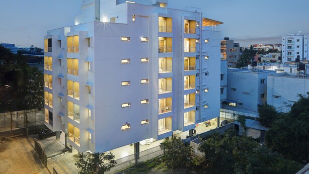 A multi-story hotel with balconies, a parking area, and a view of the surrounding cityscape. - Acasa Suites ITPL Whitefield (Bengaluru)