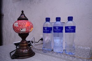 Una lámpara decorativa, tres botellas de agua y un cable de alimentación sobre una mesa.