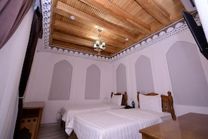 A bedroom with two beds, a wooden ceiling, and a chandelier. - Sarroj  (Bukhara)