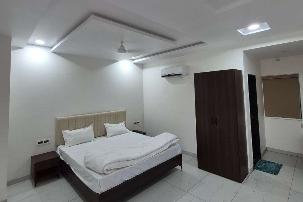 A modern bedroom with a bed, nightstands, a wardrobe, and recessed ceiling lighting.