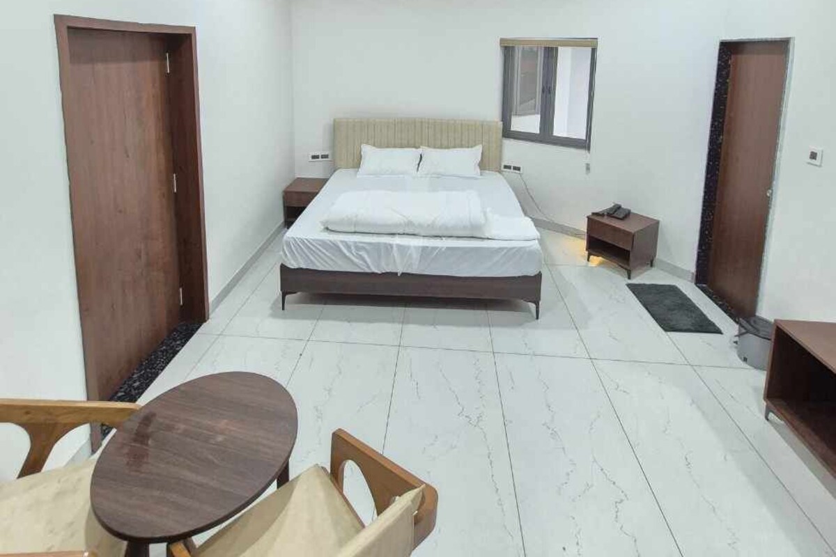 A modern bedroom with a bed, bedside tables, a small table, and a chair.