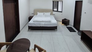 Ein modernes Schlafzimmer mit Bett, Nachttischen, Deckenventilator und einem kleinen Tisch mit Stühlen.