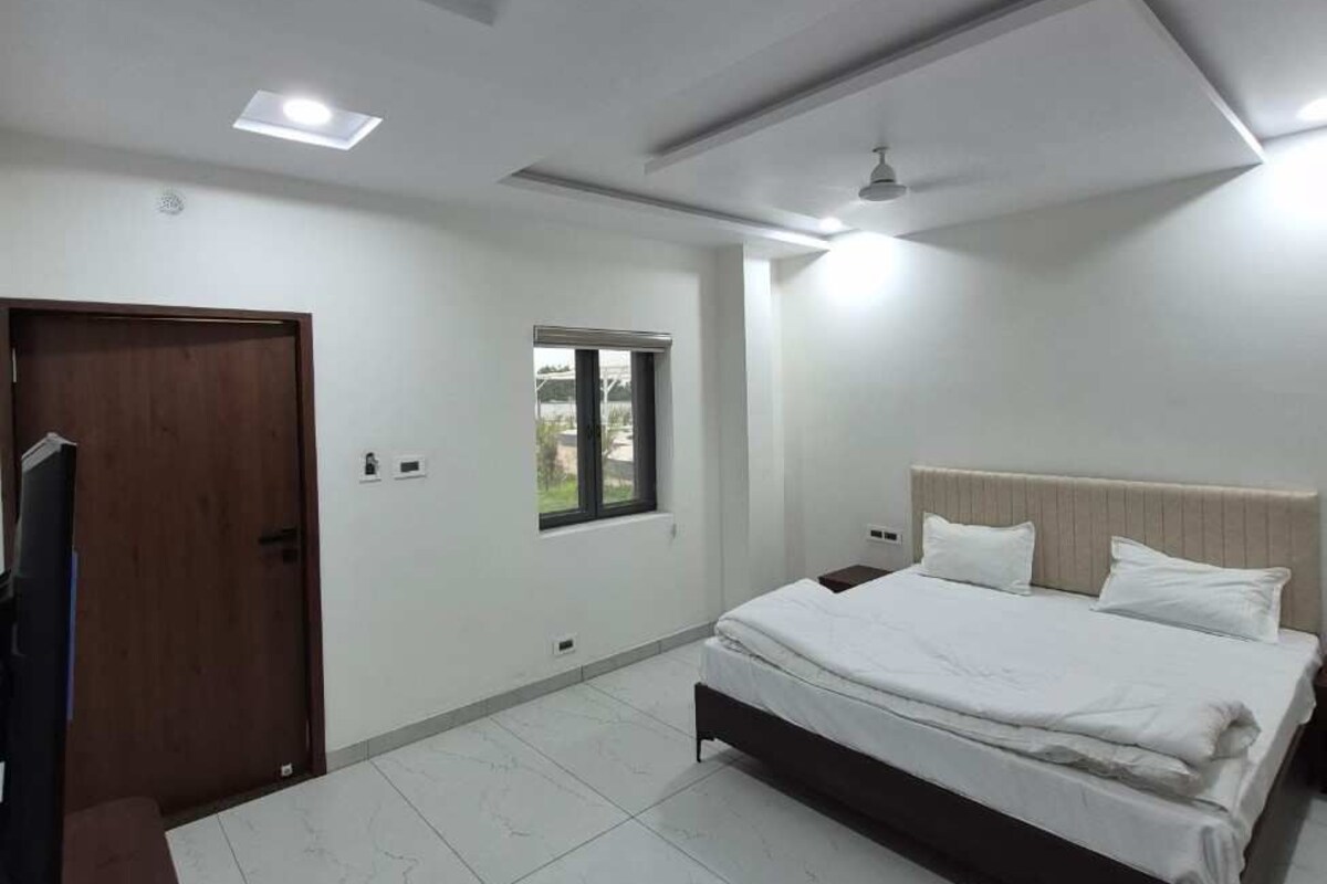 Un dormitorio con cama, televisor y ventana.