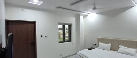 A modern bedroom with a bed, a desk, and a television.