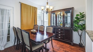 Un comedor con una mesa de madera, sillas, una araña y un aparador.