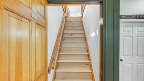 Un escalier en bois mène à un palier où se trouve une porte blanche et un meuble en bois.