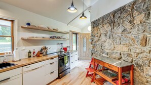 Une cuisine moderne avec des plans de travail en bois, des armoires blanches et un mur d’accent en pierre.