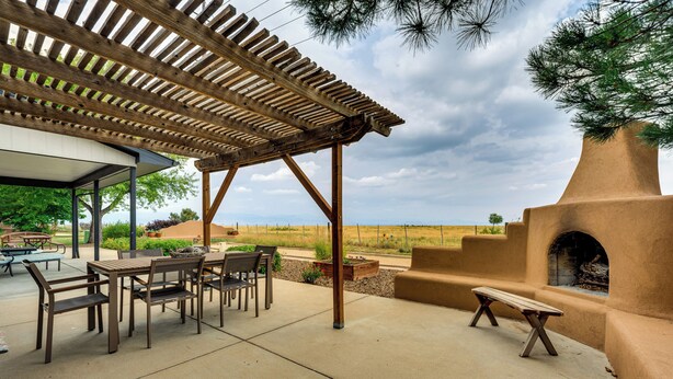 Une terrasse extérieure dotée d’une pergola, de sièges et d’une cheminée en pierre.