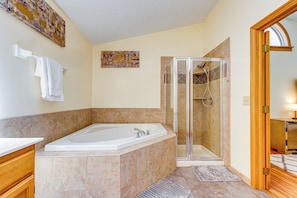 A bathroom with a large bathtub, a glass-enclosed shower, and a wooden vanity. - Families Welcome: Lake-view Home, 2 Mi to Gahanna! (Columbus)