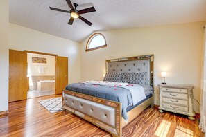 A bedroom with a bed, a dresser, a ceiling fan, and a window.