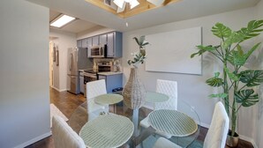 A modern kitchen with stainless steel appliances, a dining area with round glass tables and white chairs, and a ceiling fan. - 10 Mi to Dtwn Tulsa: Condo w/ Pool Access! (Tulsa)