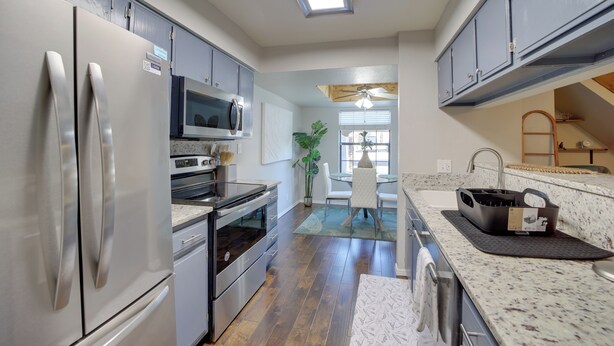 A modern kitchen with stainless steel appliances, a microwave, and a dining area with a glass table and chairs. - 10 Mi to Dtwn Tulsa: Condo w/ Pool Access! (Tulsa)