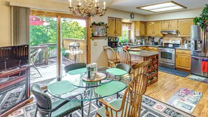 A spacious kitchen with wooden cabinets, a stainless steel refrigerator, and a dining area with a glass table and chairs. - 5 Mi to Platte River: Inviting Bellevue Rental (Bellevue)
