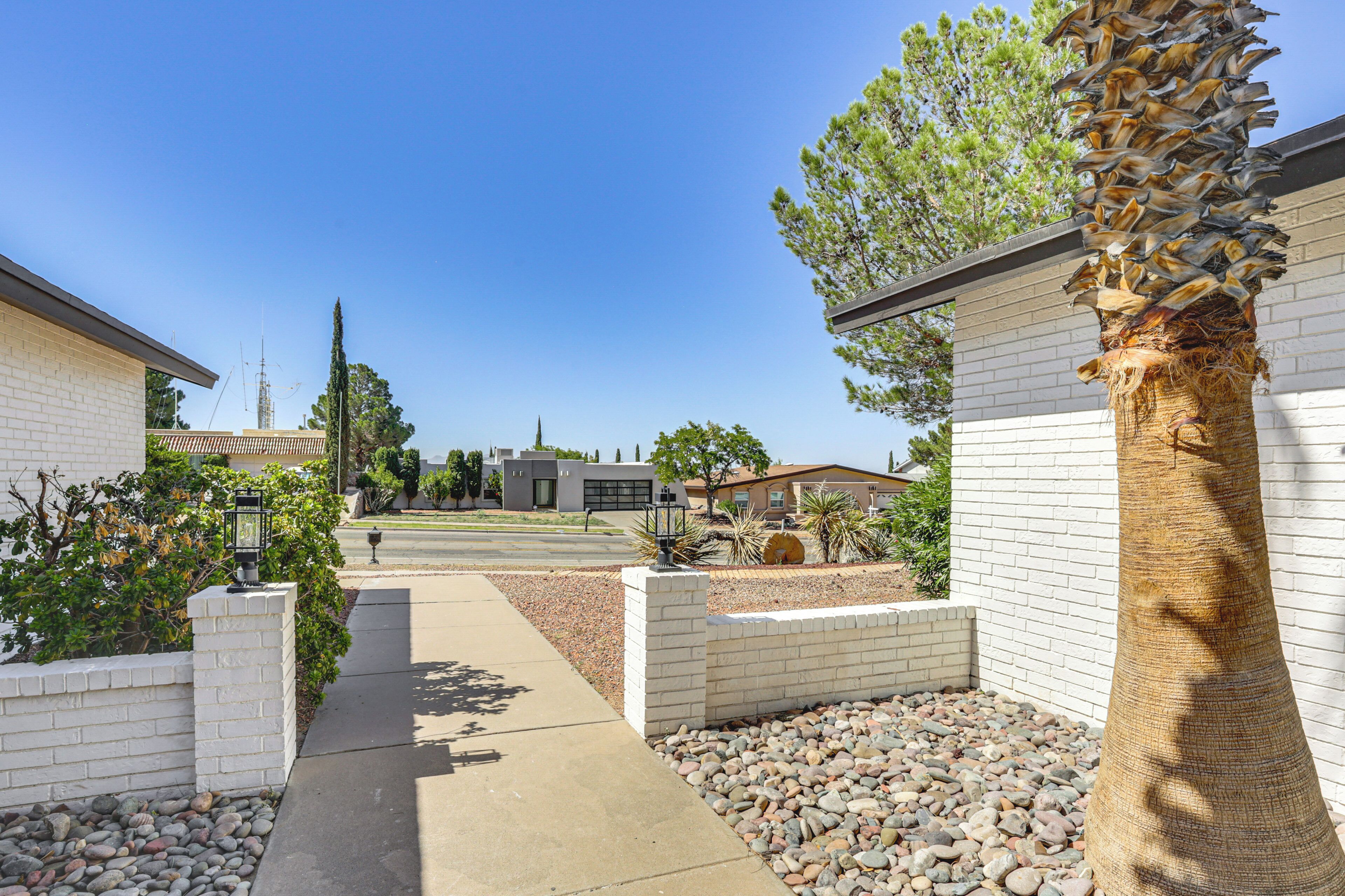 A residential area with white brick houses, a paved walkway, and a palm tree.