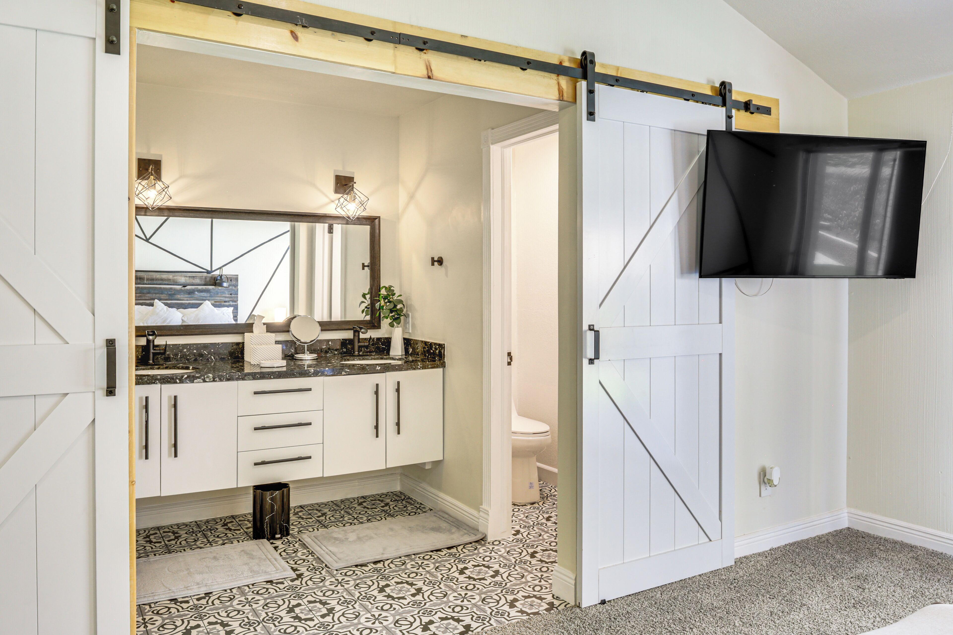Une salle de bain avec un grand miroir, un lavabo doté d’un plan de toilette en marbre et des toilettes.