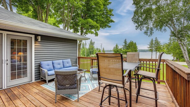 A deck with outdoor furniture, a covered patio, and a view of a lake. - Bring Your Boat! Little Traverse Lake Getaway (Maple City)