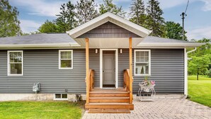 A two-story house with a front porch, a garage, and a small front yard. - Bring Your Boat! Little Traverse Lake Getaway (Maple City)