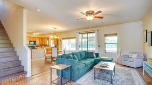 A spacious living area with a green sofa, a coffee table, and a staircase leading to the upper floor. - Southwestern Chic! Tucson Retreat w/ Private Patio (Tucson)