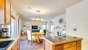 A modern kitchen with wooden cabinets, a central island, and a dining area with a round table and chairs. - Southwestern Chic! Tucson Retreat w/ Private Patio (Tucson)