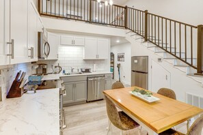 Une cuisine moderne avec des meubles blancs, des appareils en acier inoxydable et une table à manger en bois.