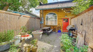 A wooden house with a red door, a wooden deck, and various potted plants. - Joliet Main Street Retreat < 30 Mi to Red Lodge (Joliet)