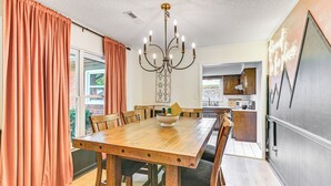 A dining area with a wooden table, chairs, and a chandelier. There is a kitchen visible in the background. - Pet-friendly Home w/ Yard, 1 Mi to Decatur Mall (Decatur)