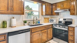 A kitchen with wooden cabinets, a stainless steel stove, a dishwasher, and a window with a view of the outside. - Pet-friendly Home w/ Yard, 1 Mi to Decatur Mall (Decatur)