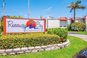 A sign for Runaway Bay Condominium with a clear view of the building's exterior.