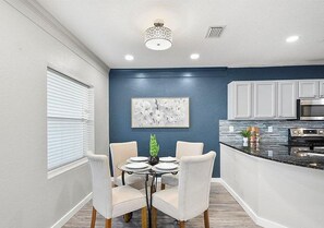 A dining area with a round table, four chairs, and a decorative plant. - New Rental Free Tickets on Short Stays (St. Augustine)
