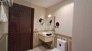 A bathroom with a dark wooden door, a sink with a mirror, a towel rack, and a toilet. - Mafaza Al-Qassim Hotel (Riyad Al Khabra)