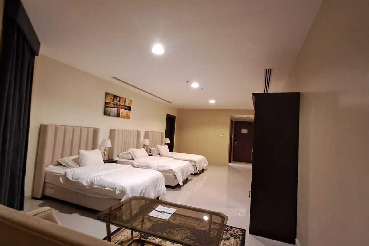 Une chambre d’hôtel avec deux lits, une table basse en verre et un tableau au mur.